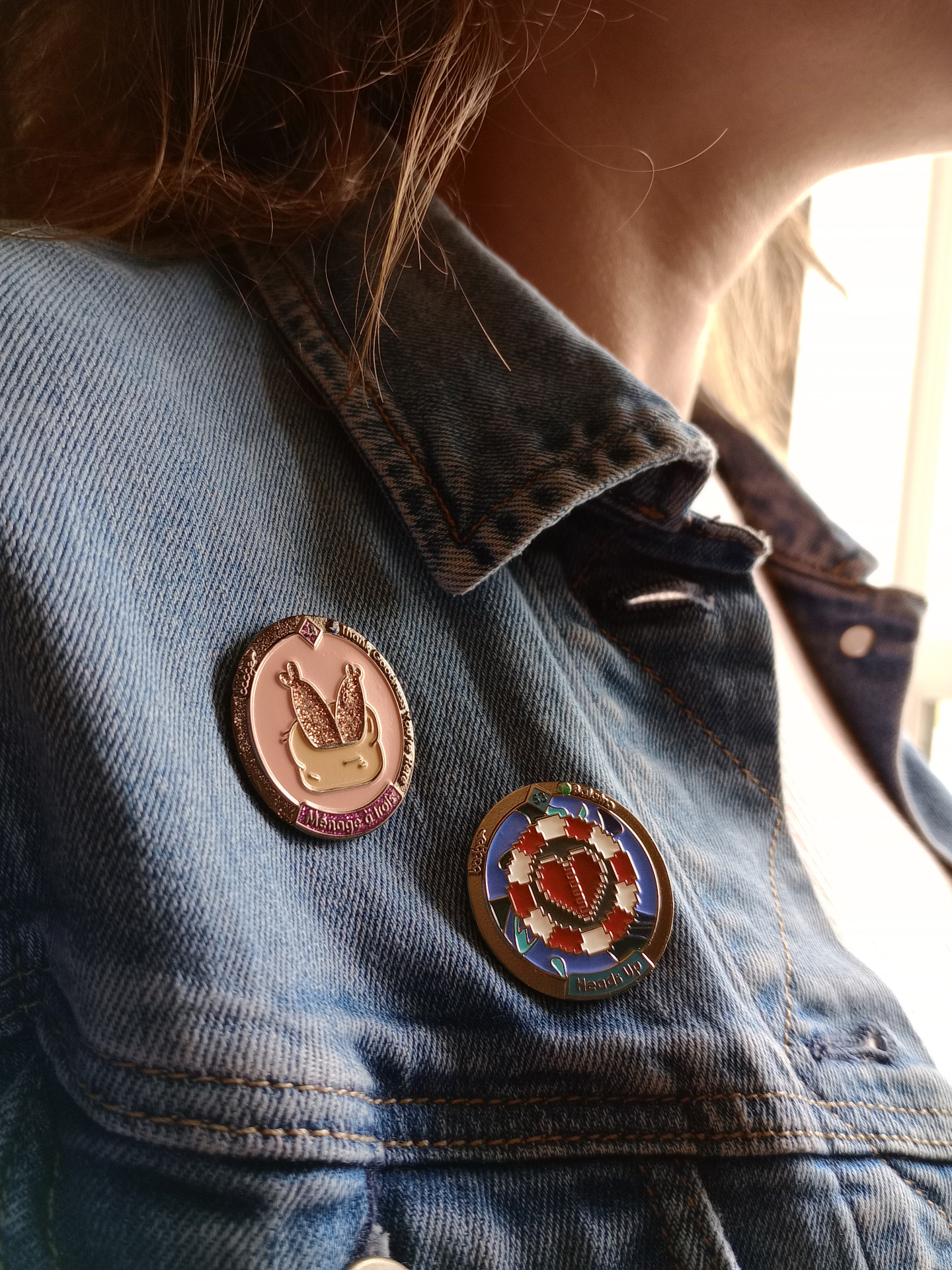 Two gaming achievement pins worn on a denim jacket